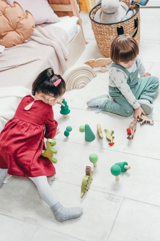 Two young children sitting on the floor enjoying playing with wooden toys.
