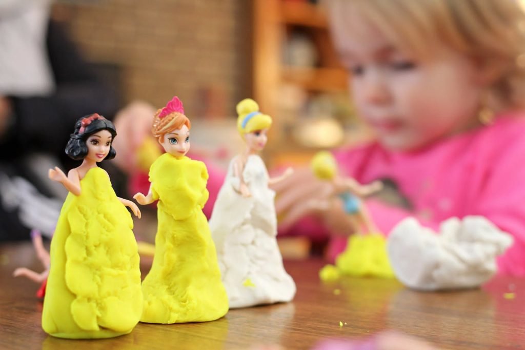 A child enjoying creative play with colorful clay figurines indoors.